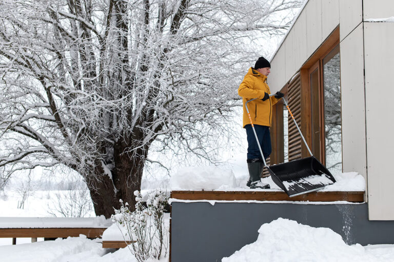 A man clearing snow from the terrace of a building