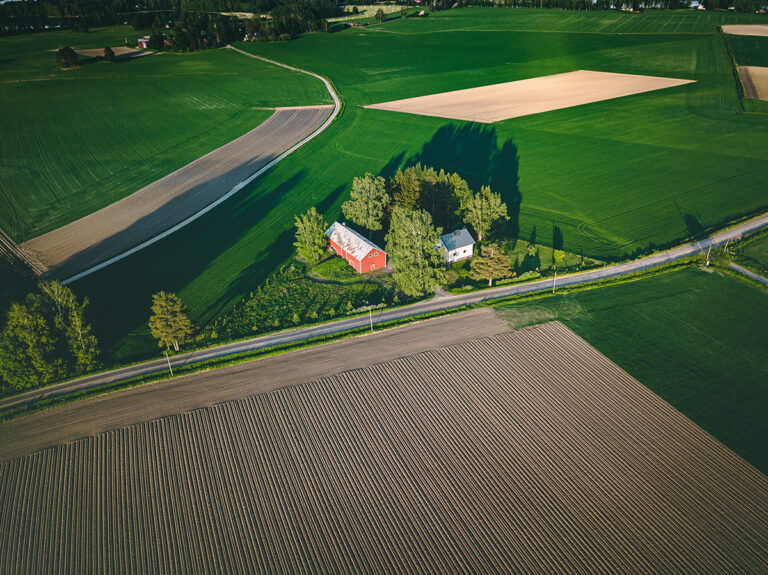 Aerial view of farmland with red barn and houses and harvest field